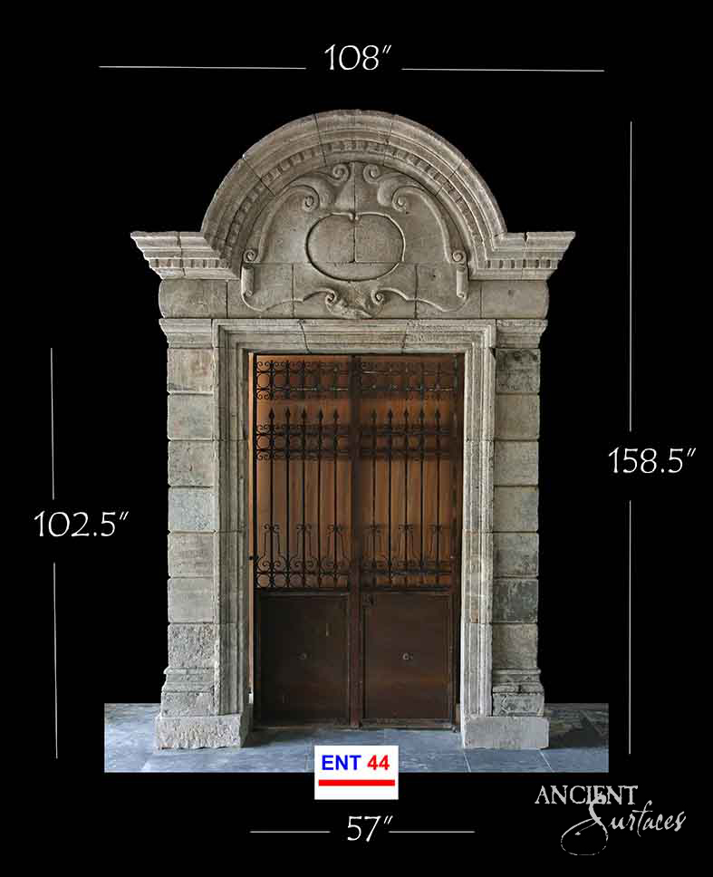Limestone doorway with a carved segmental pediment and central cartouche over ashlar jambs
