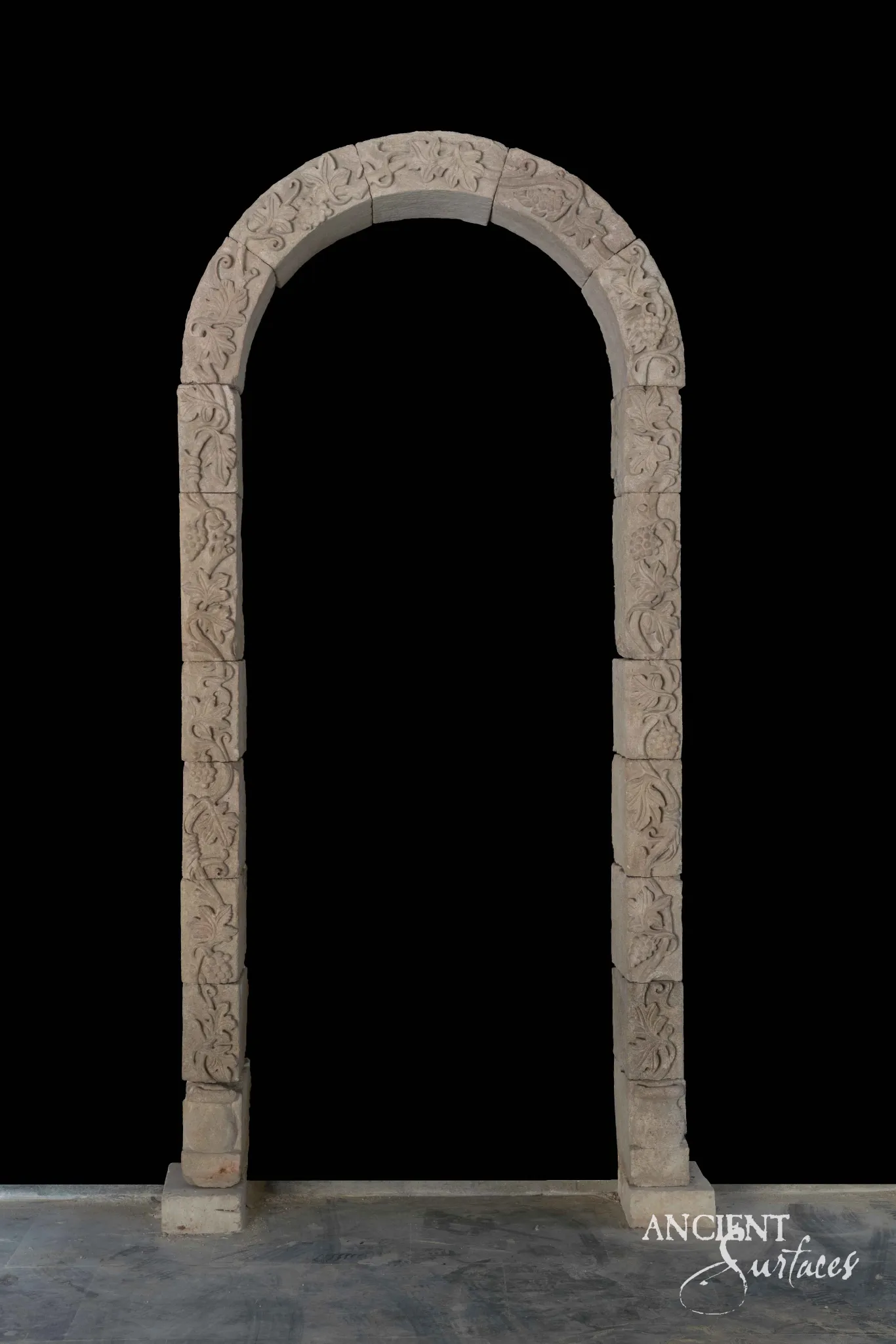 Freestanding limestone arch carved with grapevine and grape-cluster relief