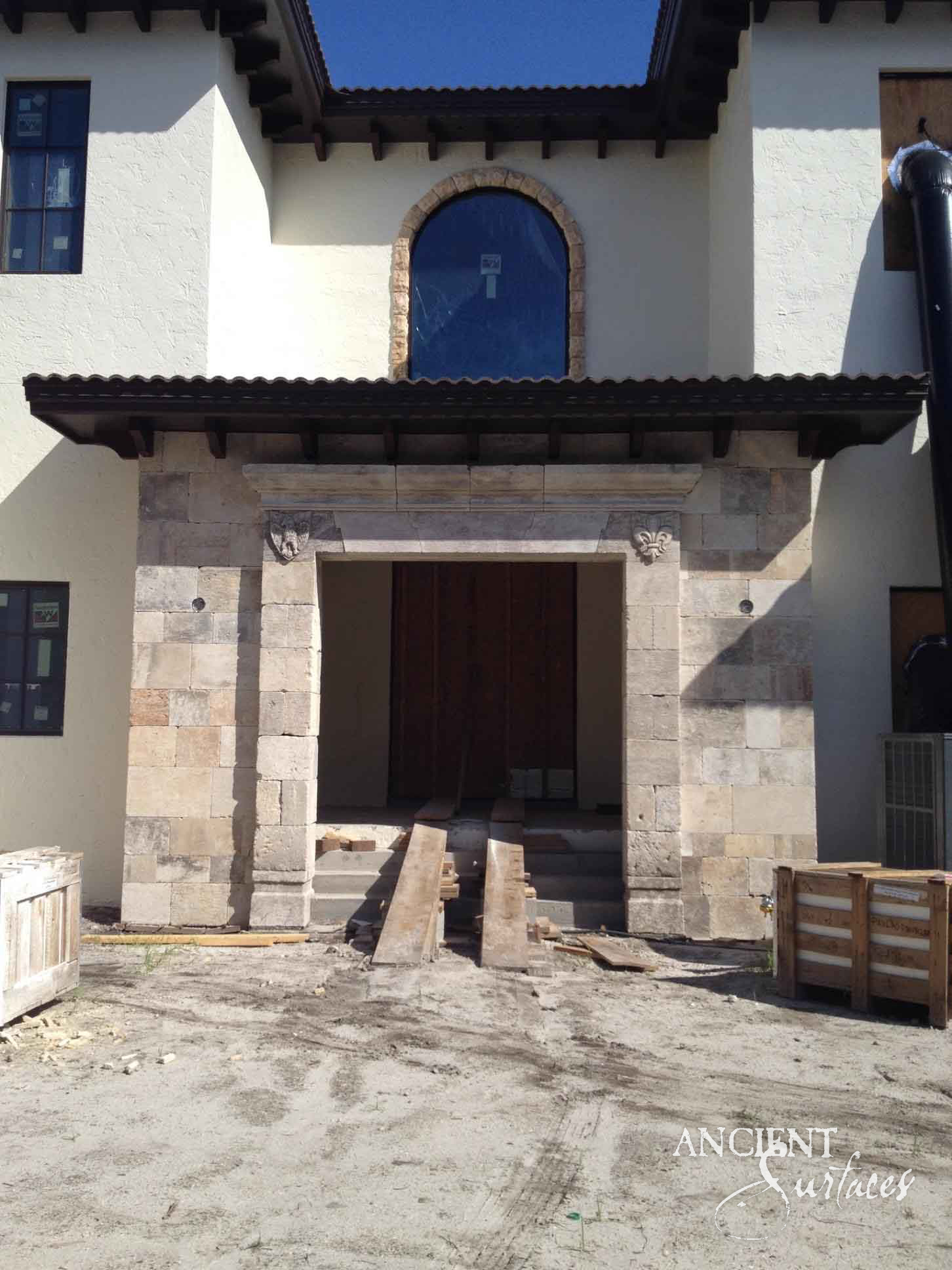 Reclaimed antique limestone entryway portal installed under a timber eave